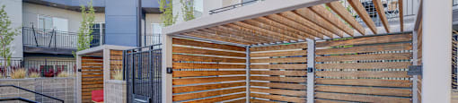 A modern outdoor seating area with red cushioned benches and a wooden slatted gate.