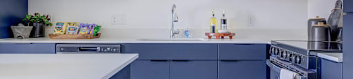 A kitchen with white countertops and blue cabinets.