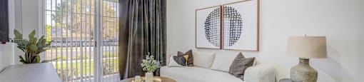 A living room with a white couch, a coffee table, and a painting on the wall.