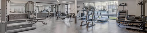 a gym with weights and cardio equipment in a building with windows