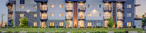 A modern apartment building with balconies and a stone facade.