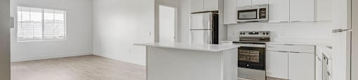 an empty kitchen with white cabinets and a white counter top