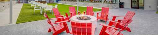 an outdoor patio with red chairs and a fire pit