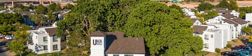 an aerial view of a large white house with a brown roof and a parking lot