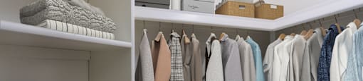 A white closet with clothes hanging and folded items on shelves.