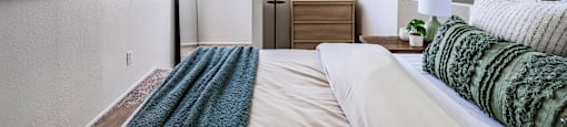 A bedroom with a bed, nightstand, and a painting on the wall.
