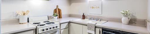 A white kitchen with a stove, sink, and oven.