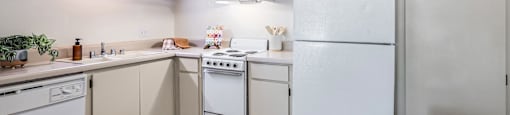 A kitchen with white appliances and wooden floors.