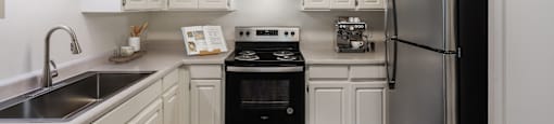 A kitchen with white cabinets and a black fridge.