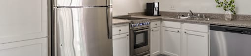 an empty kitchen with stainless steel appliances and white cabinets