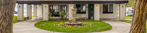 a house with a fountain in the center of a circle of grass