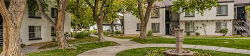 a sidewalk with trees and apartments in the background