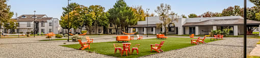 a park with orange tables and chairs on the grass