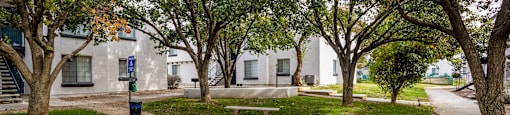 a park with benches and trees in front of a building