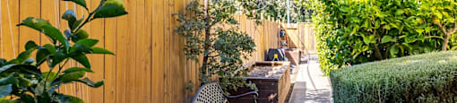 A black metal bench sits in a garden next to a wooden fence.