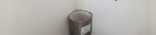 a white room with two mirrors on the wall and a trash can