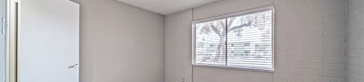 an empty living room with wood flooring and a window
