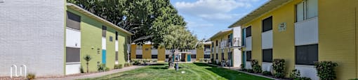 a row of yellow and white houses with grass and trees