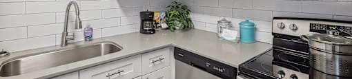 a kitchen with white cabinets and a sink and a stove