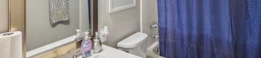 a bathroom with a blue shower curtain and a toilet and sink