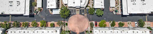 A bird's eye view of a parking lot with a roundabout and a pool in the middle of the buildings.