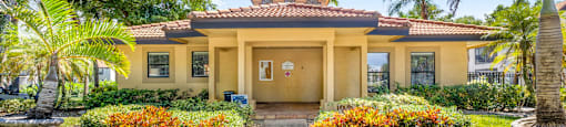 A yellow house with a red tile roof and a brown door.