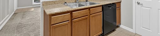A kitchen with wooden cabinets and a black dishwasher.