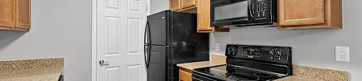 A kitchen with black appliances and wooden cabinets.