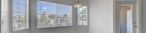 an empty living room with three windows and a door