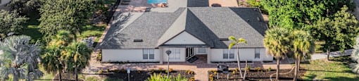 A large house with a pool in the middle of a lake surrounded by trees. at Cascades at Clear Lake Apartments, Ft. Myers, FL, 33908