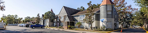 A car is parked in a parking lot in front of a building with a tower. at Foxcroft Apartments, Tampa, FL, 33614