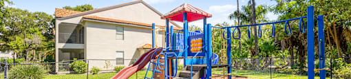 A playground with a red slide and blue monkey bars.