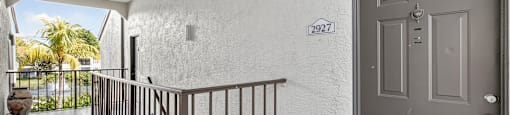 A balcony with a metal railing and a brown door with a number 2927 on it.