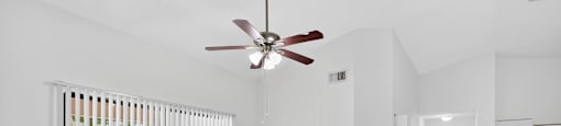 A room with a ceiling fan and a window with blinds.
