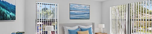 A bedroom with a large bed, a ceiling fan, and a painting of a beach scene on the wall.