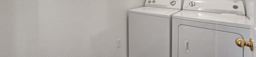 an empty room with a washer and dryer in it and a white wall
