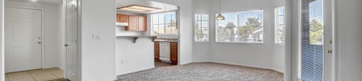 an empty living room with a door to a kitchen