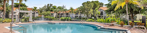 A large outdoor swimming pool surrounded by palm trees.