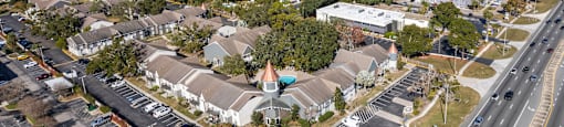 A road with cars and a building with a red roof. at Foxcroft Apartments, Tampa, Florida