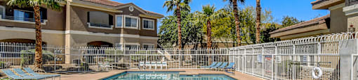 A pool surrounded by a fence and palm trees.