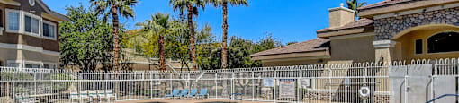 A pool surrounded by a fence with palm trees in the background.