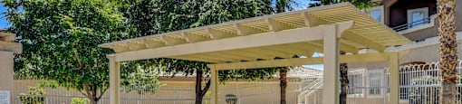 A white pergola is over a green lawn.