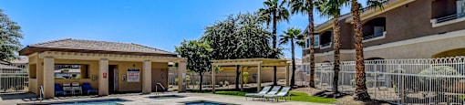 A swimming pool surrounded by palm trees and a building in the background.