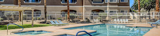 A swimming pool in front of a building with palm trees.