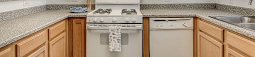 A kitchen with wooden cabinets and a white stove top oven.