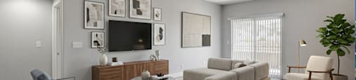 A living room with a grey couch, a blue chair, a wooden cabinet, a television, and a potted plant.