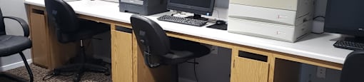 A room with a carpeted floor and a row of computers on a desk.