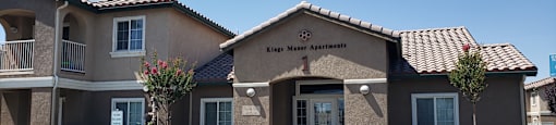 A white car is parked in front of King Maer Apartments.