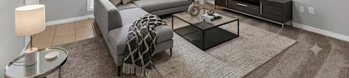 A living room with a grey couch, a coffee table, and a painting on the wall.