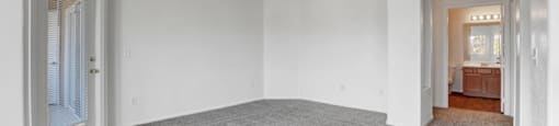 A large empty room with grey carpeting and white walls.